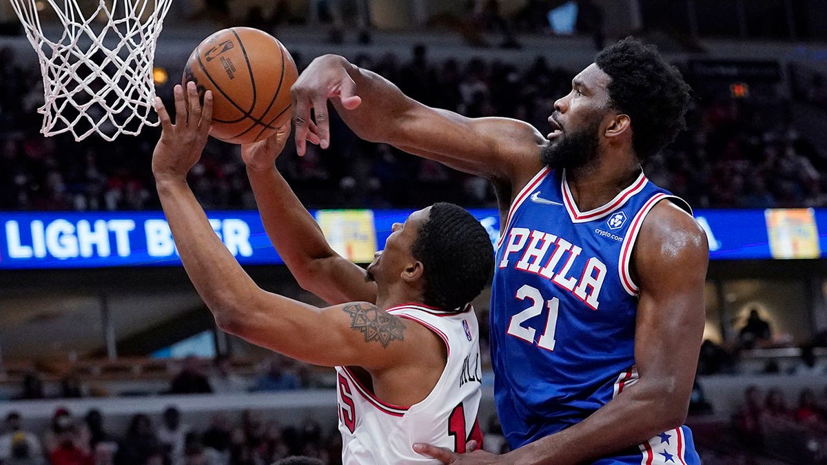Philadelphia 76ers center Joel Embiid, right, blocks a shot by Chicago Bulls forward Malcolm Hill during the second half of an NBA basketball game in Chicago, Sunday, Feb. 6, 2022.