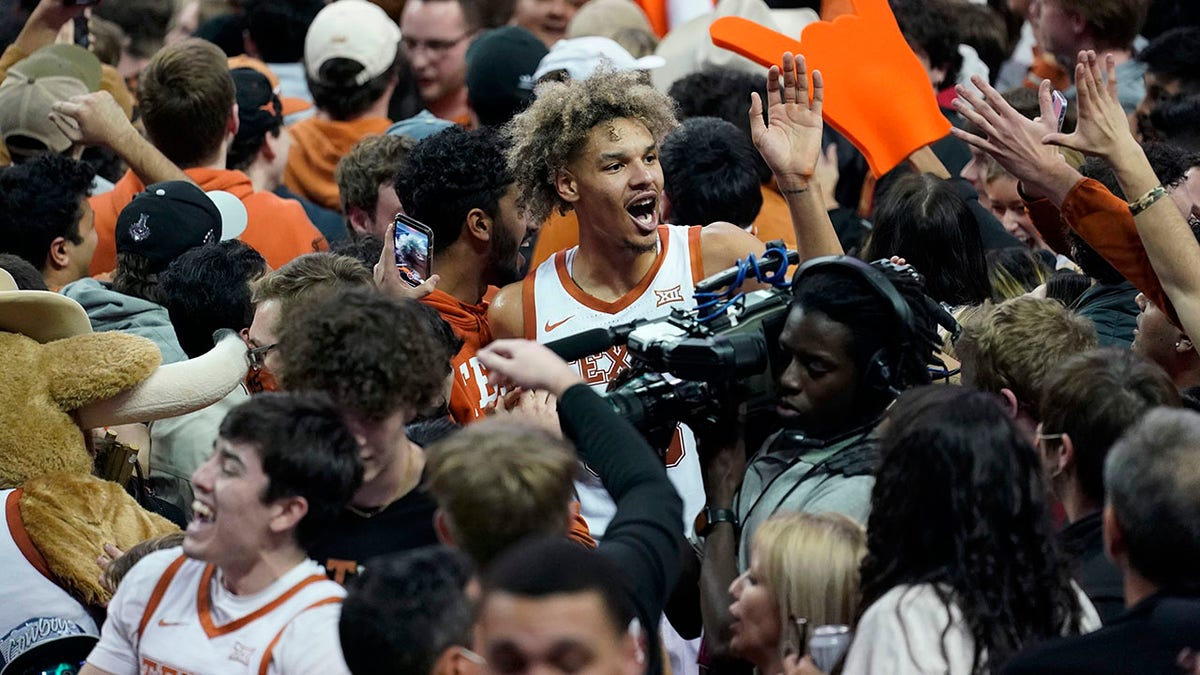 Texas forward Tre Mitchell, center, celebrates with fans as they storm the court after Texas' win over Kansas in an NCAA college basketball game, Monday, Feb. 7, 2022, in Austin, Texas.