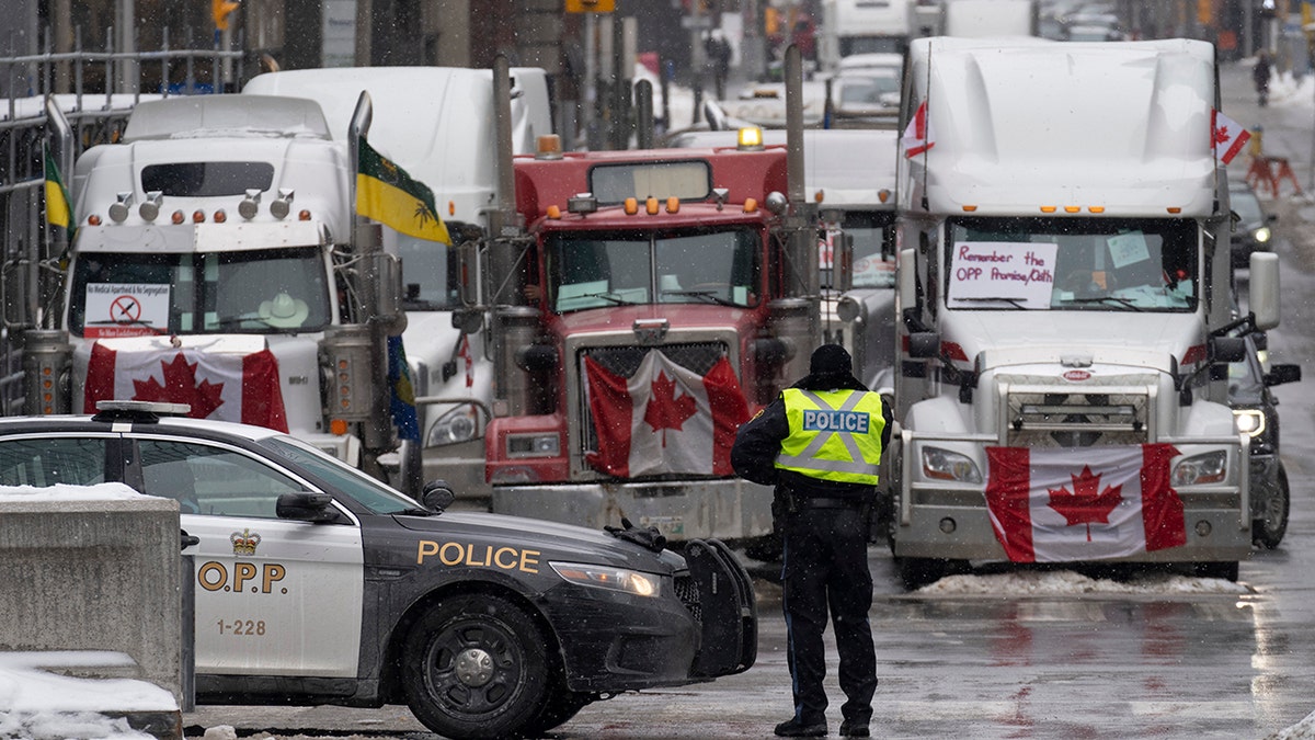 Police man a barricade in front of vehicles parked as part of the trucker protest, Tuesday, Feb. 8, 2022 in Ottawa's downtown core. (Adrian Wyld /The Canadian Press via AP)
