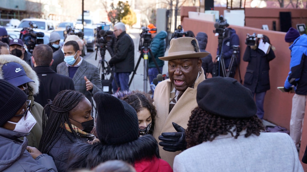 Attorney Ben Crump, center, speaks to residents of a building that had a fatal fire last month in the Bronx borough of New York, Tuesday, Feb. 8, 2022. (AP Photo/Seth Wenig)