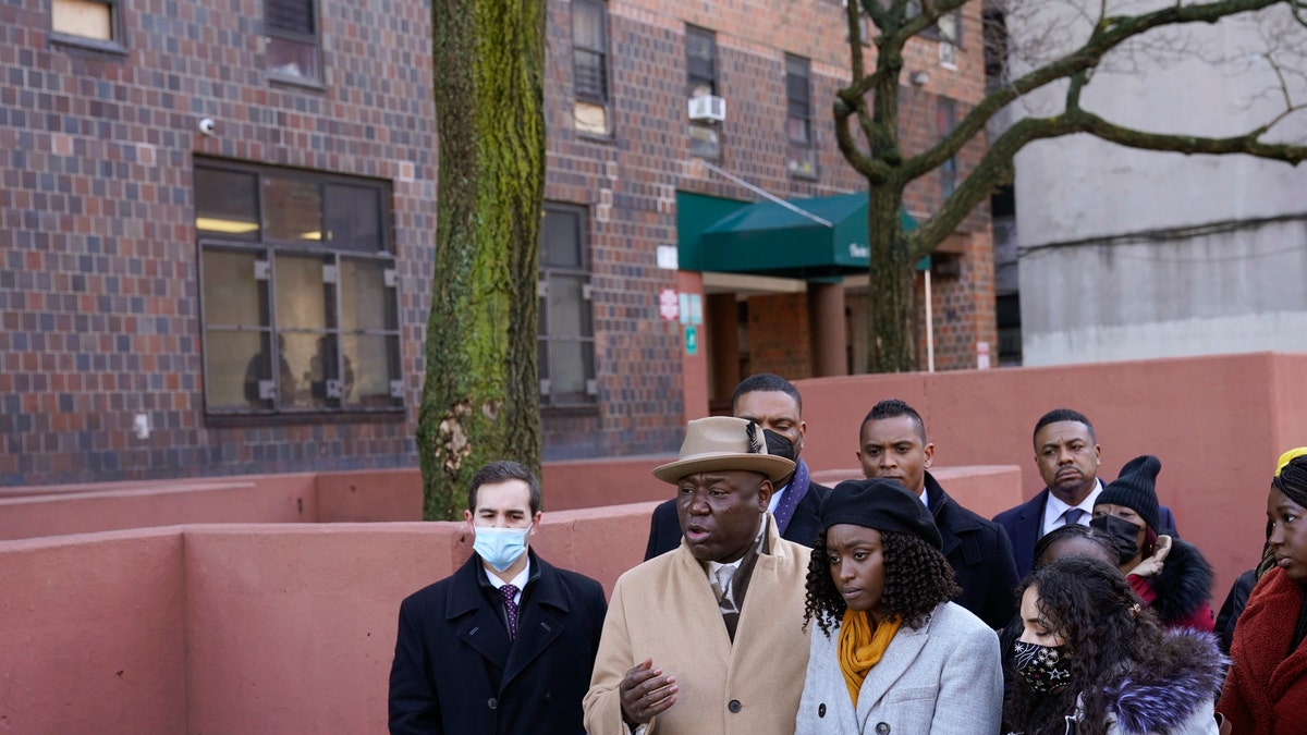Surrounded by victims of a building fire and their families, attorney Ben Crump, second from left, speaks to reporters at a news conference in the Bronx borough of New York, Tuesday, Feb. 8, 2022. (AP Photo/Seth Wenig)