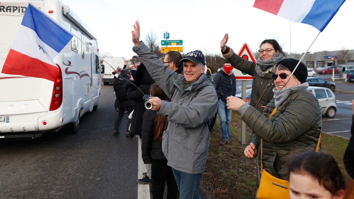 People wave to a convoy departing for Paris, Friday, Feb.11, 2022 in Strasbourg, eastern France. Authorities in France and Belgium have banned road blockades threatened by groups organizing online against COVID-19 restrictions. The events are in part inspired by protesters in Canada.