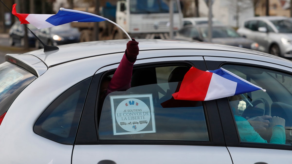 Protesters wave French flags from a car in a convoy departing for Paris, Friday, Feb.11, 2022 in Strasbourg, eastern France.
