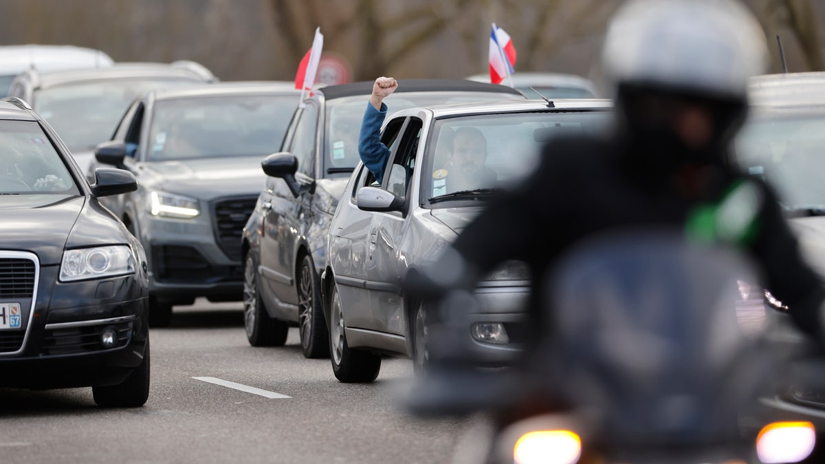 A protester clenches his fist from his car part of a convoy heading to Paris, Friday, Feb.11, 2022 in Strasbourg, eastern France.