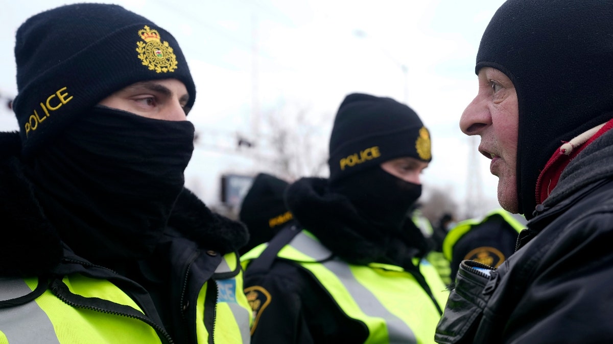 A protester yells at police officers as demonstrators prepare to leave in advance of police enforcing an injunction against their demonstration, which has blocked traffic across the Ambassador Bridge by protesters against COVID-19 restrictions, in Windsor, Ont., Saturday, Feb. 12, 2022. THE CANADIAN PRESS/Nathan Denette