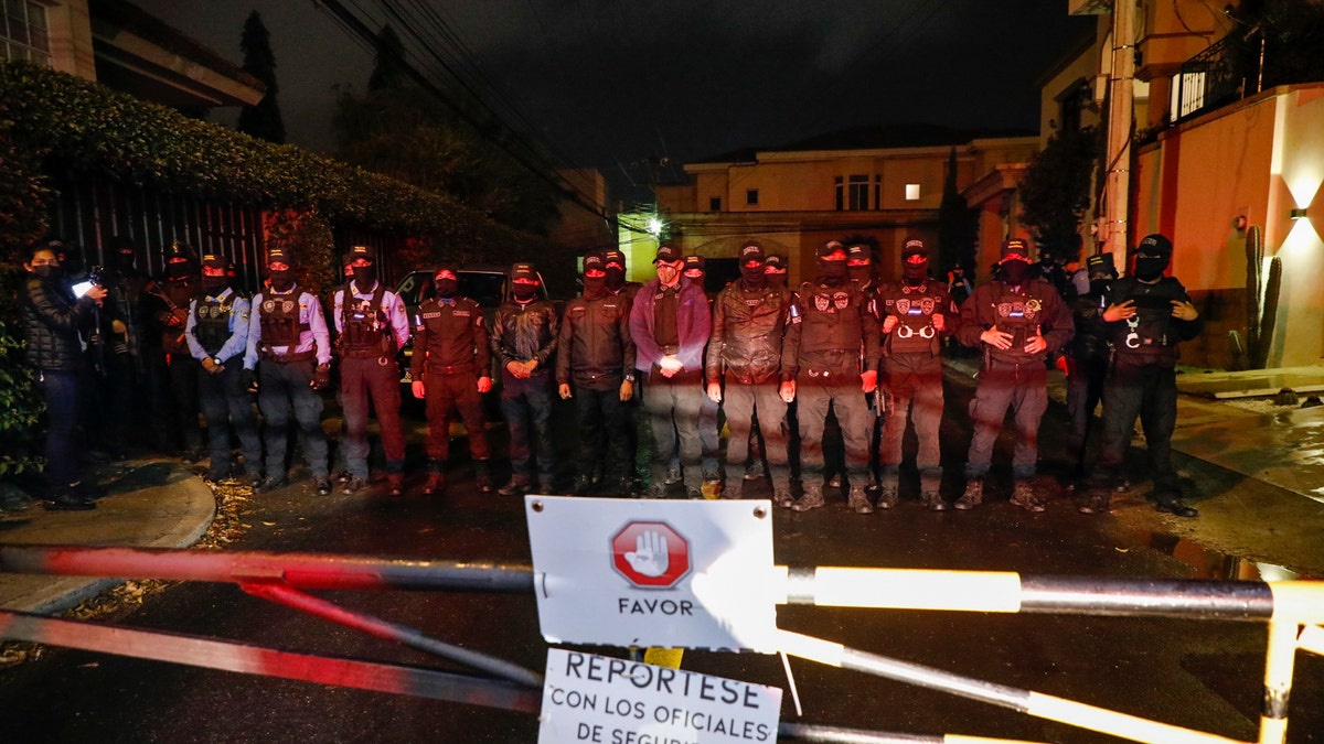 Special Forces Police block a street near the house of former Honduran President Juan Orlando Hernandez, behind a residential sign that reads in Spanish "Please, check in with security," in Tegucigalpa, Honduras, late Monday, Feb. 14, 2022. 