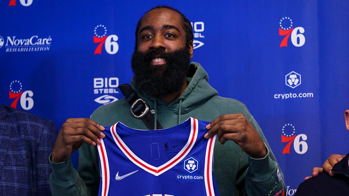 Philadelphia 76ers' James Harden holds up his new jersey after taking questions from the media at a press conference at the NBA basketball team's facility, Tuesday, Feb. 15, 2022, in Camden, N.J.