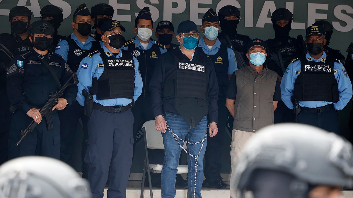 Former Honduran President Juan Orlando Hernandez, center in chains, is shown to the press at the Police Headquarters in Tegucigalpa, Honduras, Tuesday, Feb. 15, 2022. 