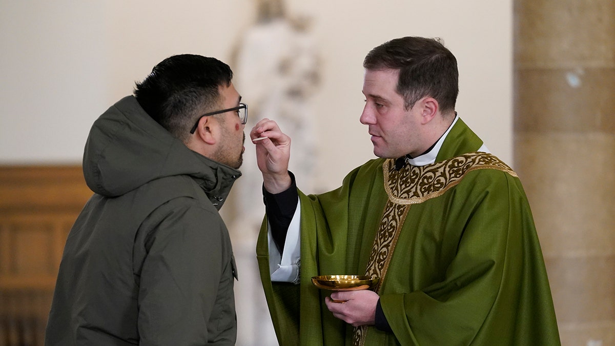 Father Matthew Hood distributes Holy Communion at Our Lady of the Rosary church Friday, Feb. 18, 2022, in Detroit. (AP Photo/Paul Sancya)