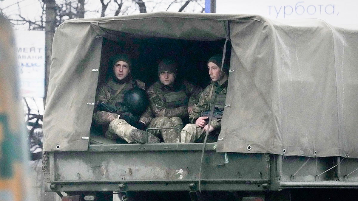 Ukrainian soldiers ride in a military vehicle in Mariupol, Ukraine