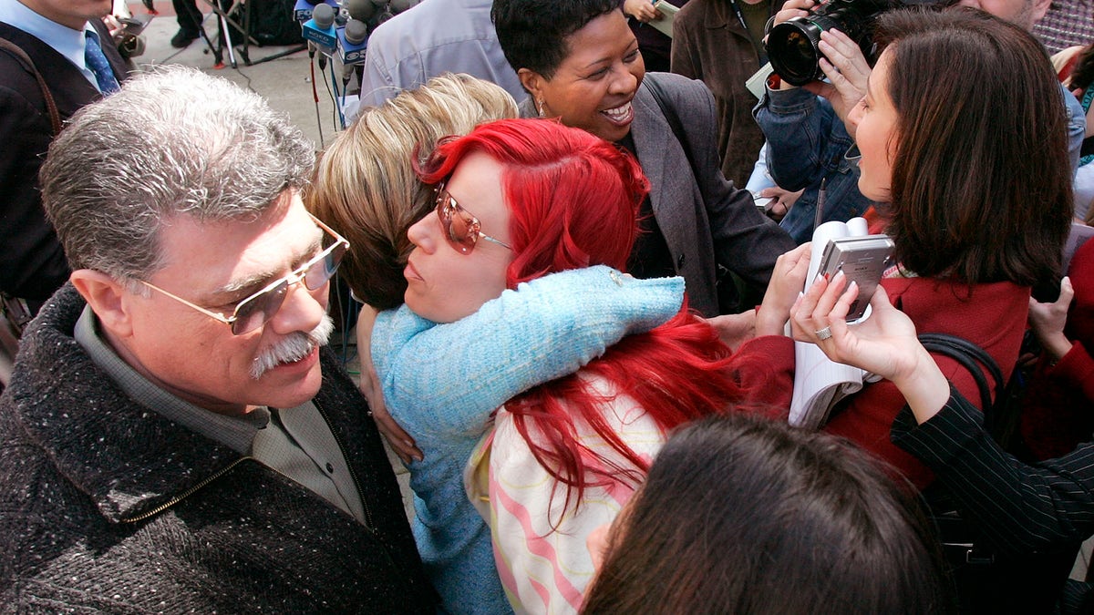 Juror Richelle Nice, center, hugs attorney Gloria Allred after speaking at a news conference after the formal sentencing of Scott Peterson in Redwood City, California, on March 16, 2005.