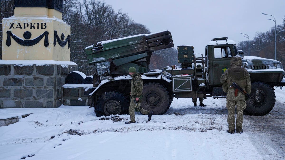 Ukrainian service members walk by a deactivated Russian military multiple rocket launcher on the outskirts of Kharkiv, Ukraine, Friday, Feb. 25, 2022.