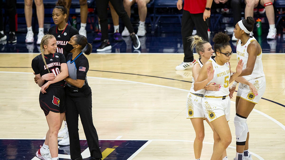 An official holds Louisville's Hailey Van Lith (10) while Notre Dame's Dara Mabrey holds teammate Olivia Miles (5), next to Maya Dodson (0) after an altercation on the court during the first half of an NCAA college basketball game Sunday, Feb. 27, 2022, in South Bend, Ind.