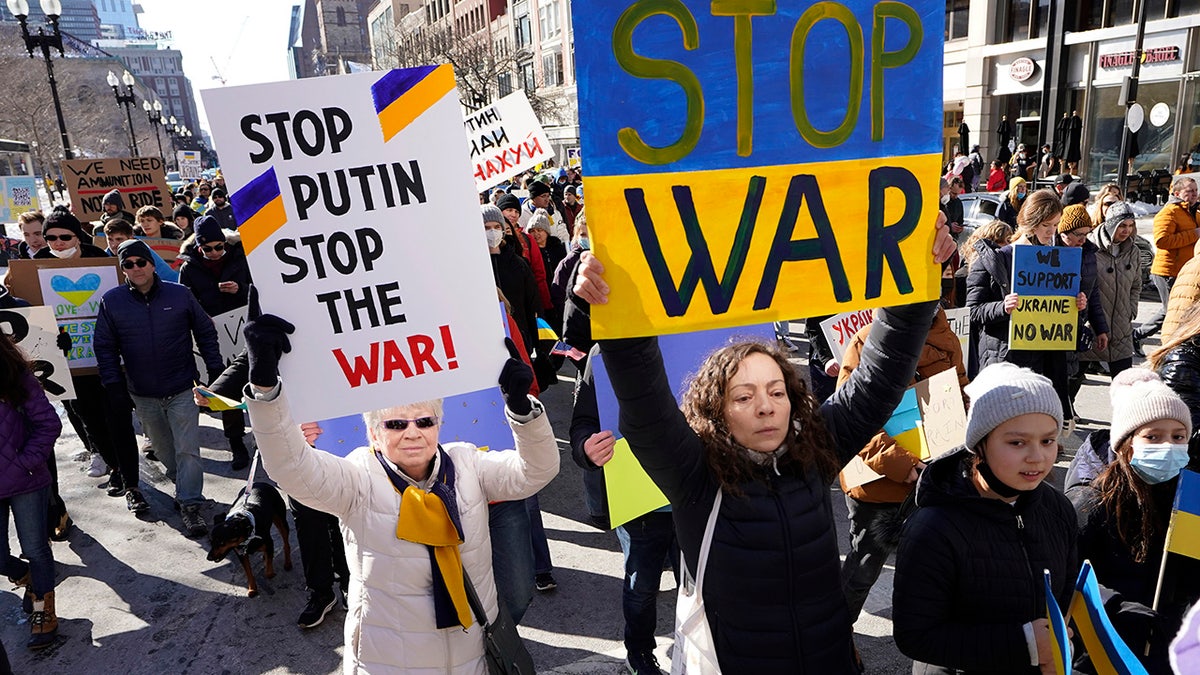 Demonstrators display placards as they march during a rally in support of Ukraine, Sunday, Feb. 27, 2022, in Boston.