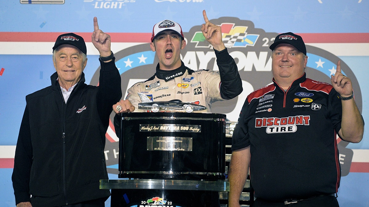 Austin Cindric, center, celebrates in Victory Lane with car owner Roger Penske, left, and crew chief Jeremy Bullins after winning the NASCAR Daytona 500 auto race at Daytona International Speedway, Sunday, Feb. 20, 2022, in Daytona Beach, Florida.