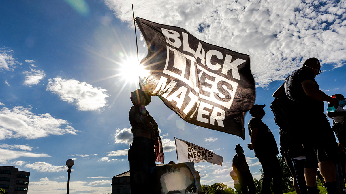 Woman holds Black Lives Matter flag at outdoor rally