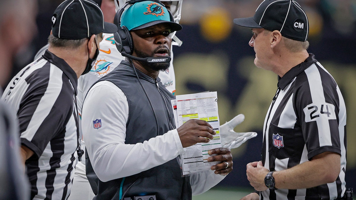 FILE - Miami Dolphins head coach Brian Flores, center, talks to down judge David Oliver (24) during the first half of an NFL football game against the New Orleans Saints Monday, Dec. 27, 2021, in New Orleans.