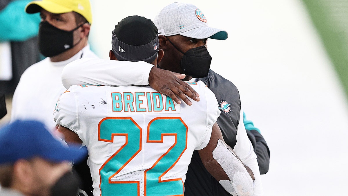 Head coach Brian Flores of the Miami Dolphins hugs Matt Breida on the sidelines during their NFL game against the New York Jets at MetLife Stadium on Nov. 29, 2020, in East Rutherford, New Jersey.