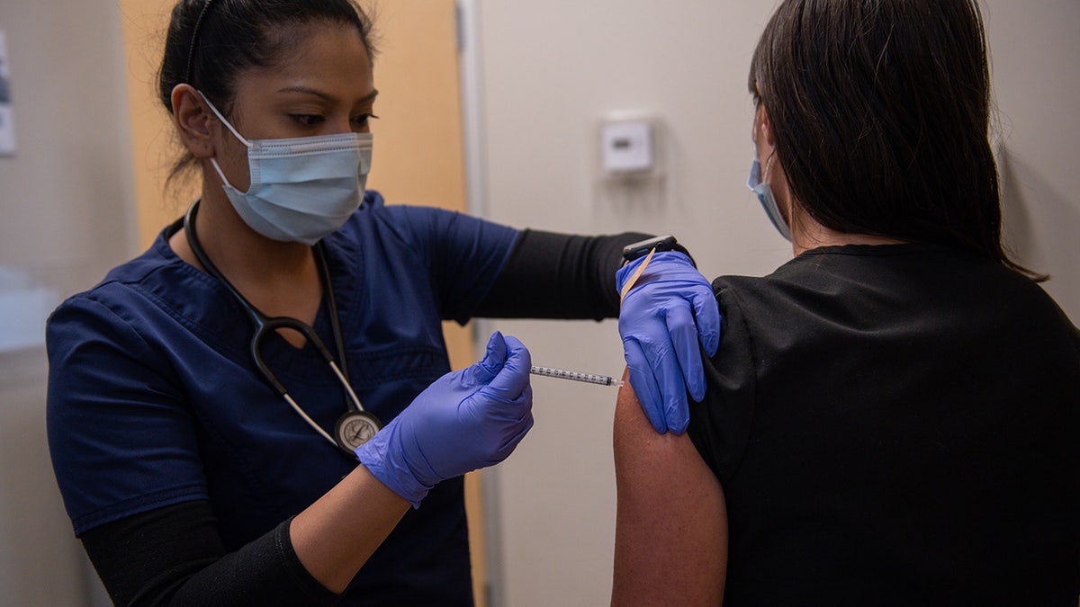 A health care worker administers a third dose of the Moderna COVID-19 vaccine at the CareNow Denver University urgent care center in Denver, Colorado, on Tuesday, Nov. 16, 2021.
