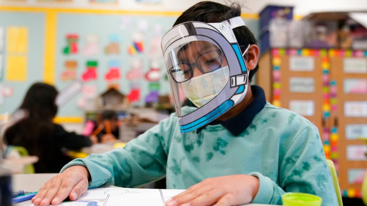 FILE - A student wears a mask and face shield in a 4th grade class amid the COVID-19 pandemic at Washington Elementary School on Jan. 12, 2022, in Lynwood, Calif. Gov. Gavin Newsom delayed a closely watched decision on lifting California's school mask mandate Monday, Feb. 14 even as other Democratic governors around the country have dropped them in recent weeks. (AP Photo/Marcio Jose Sanchez, File) 