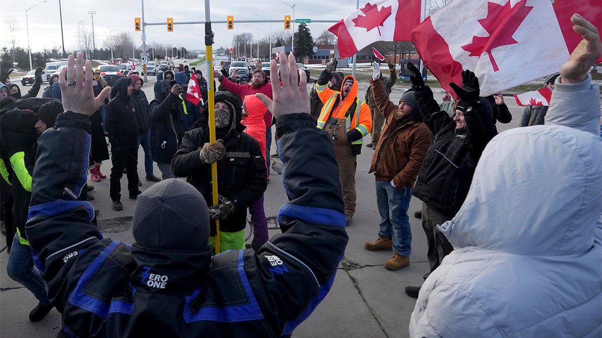 Protesters sing the Canadian national anthem prior to police action to enforce an injunction against a demonstration which has blocked traffic across the Ambassador Bridge by protesters against COVID-19 restrictions, in Windsor, Ont., Saturday, Feb. 12, 2022.