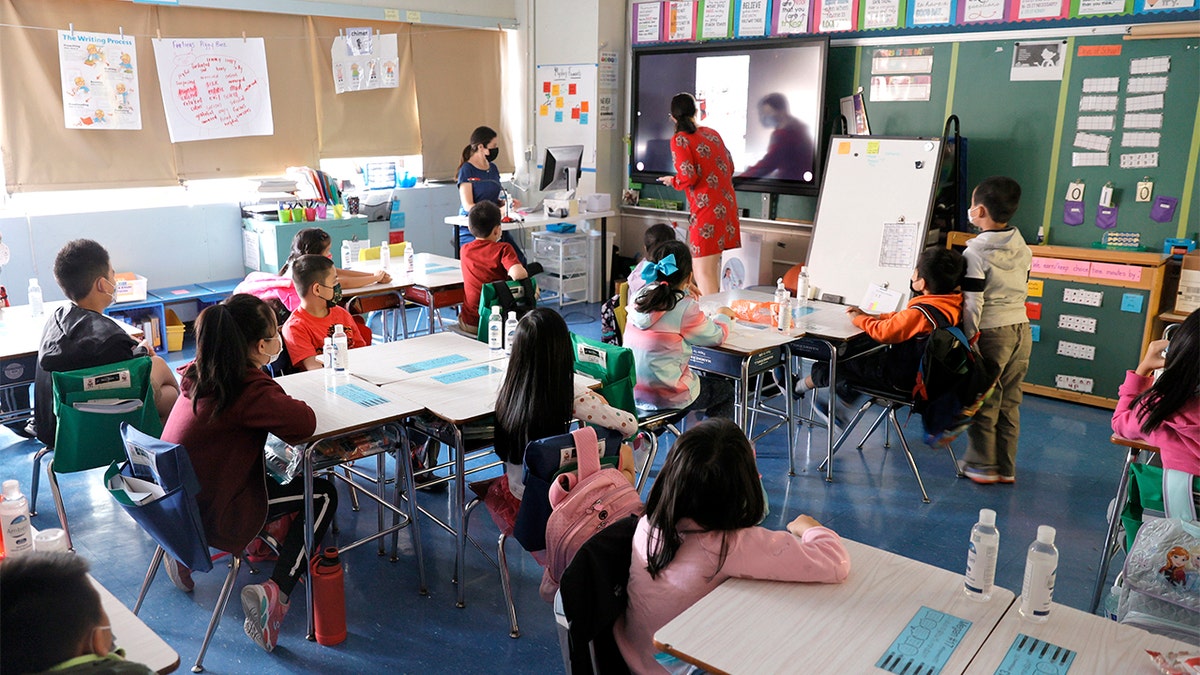 NEW YORK, NEW YORK - SEPTEMBER 27: (L-R) Co-teachers at Yung Wing School P.S. 124 Marisa Wiezel (who is related to the photographer) and Caitlin Kenny give a lesson to their masked students in their classroom on September 27, 2021 in New York City. New York City schools fully reopened earlier this month with all in-person classrooms and mandatory masks on students. The city's mandate ordering all New York City school staff to be vaccinated by midnight today was delayed again after a federal appeals court issued a temporary injunction three days before the mayor's deadline. (Photo by Michael Loccisano/Getty Images)