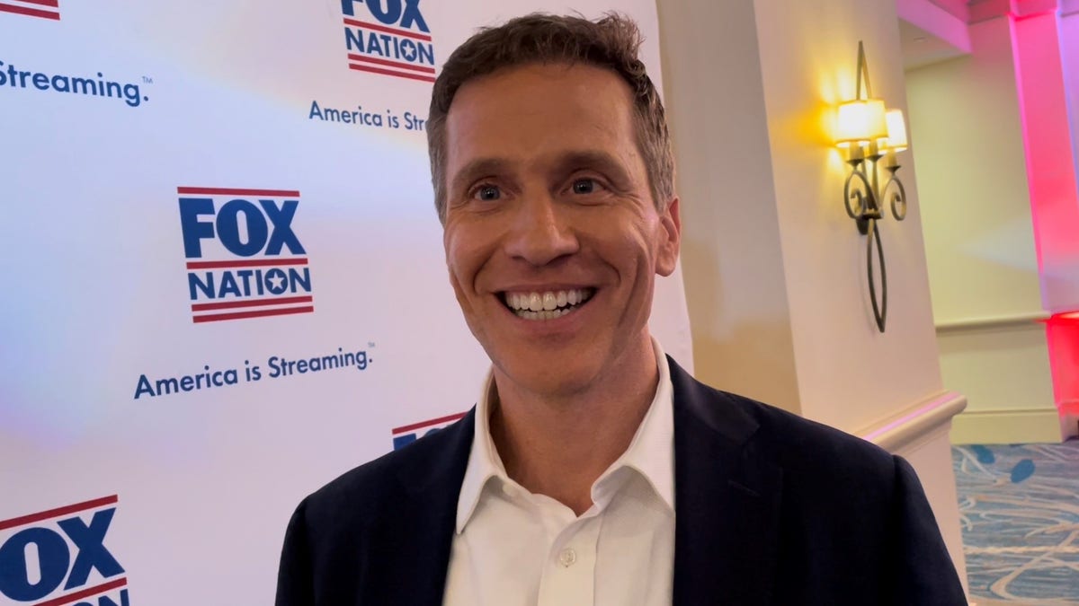 Eric Greitens in a suit at CPAC in front of a Fox Nation setup