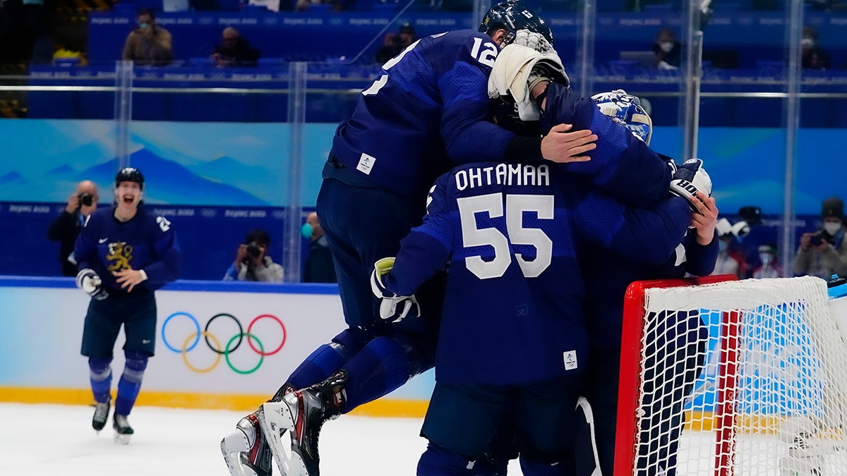 Finland's Marko Anttila (12) jumps on Atte Ohtamaa (55) and goalkeeper Harri Sateri after Finland beat Russian Olympic Committee to win the men's gold medal hockey game at the 2022 Winter Olympics, Sunday, Feb. 20, 2022, in Beijing.