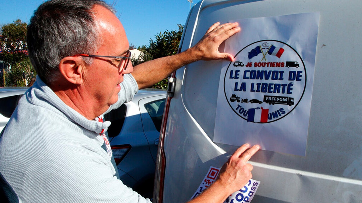 A man puts a poster reads "Liberty Convoy" on a van before leaving for Paris , in Bayonne, southwestern France, Wednesday, Feb.9, 2022.