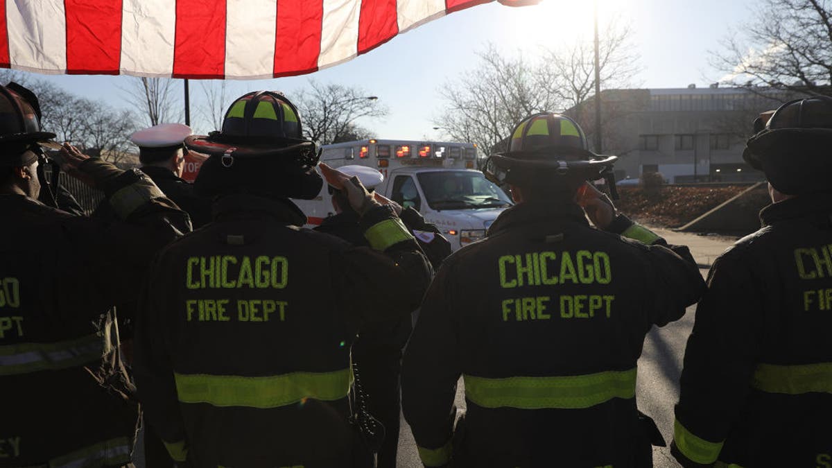 Chicago firefighters salute the ambulance arriving at the Medical Examiners office with the body of an off duty police officer shot and killed in Chicago on Saturday, March 23, 2019.