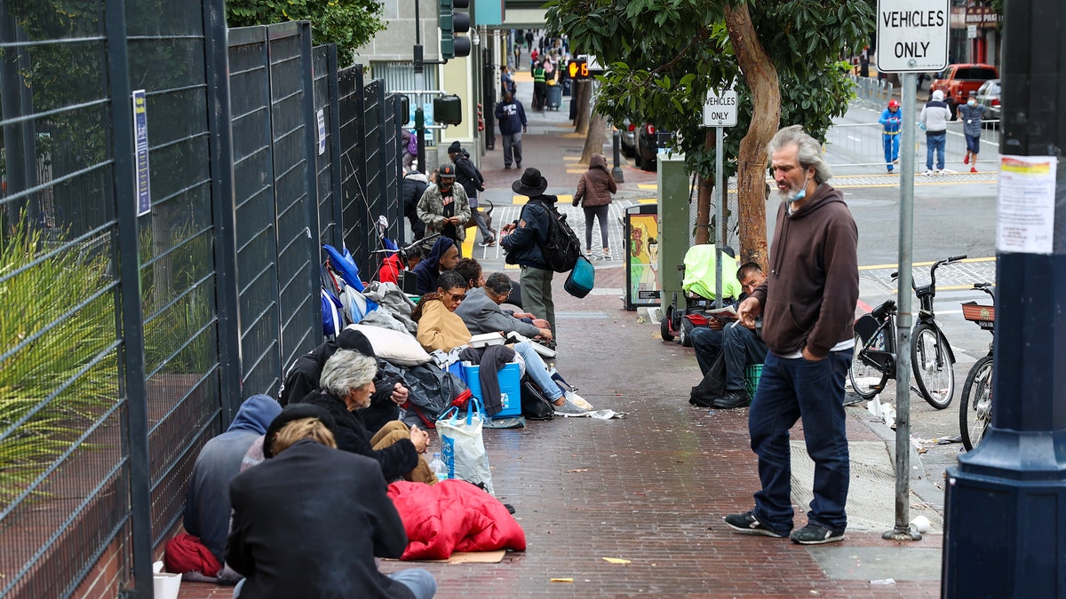 Photo shows homeless people in San Francisco standing and sitting outside in the Tenderloin district