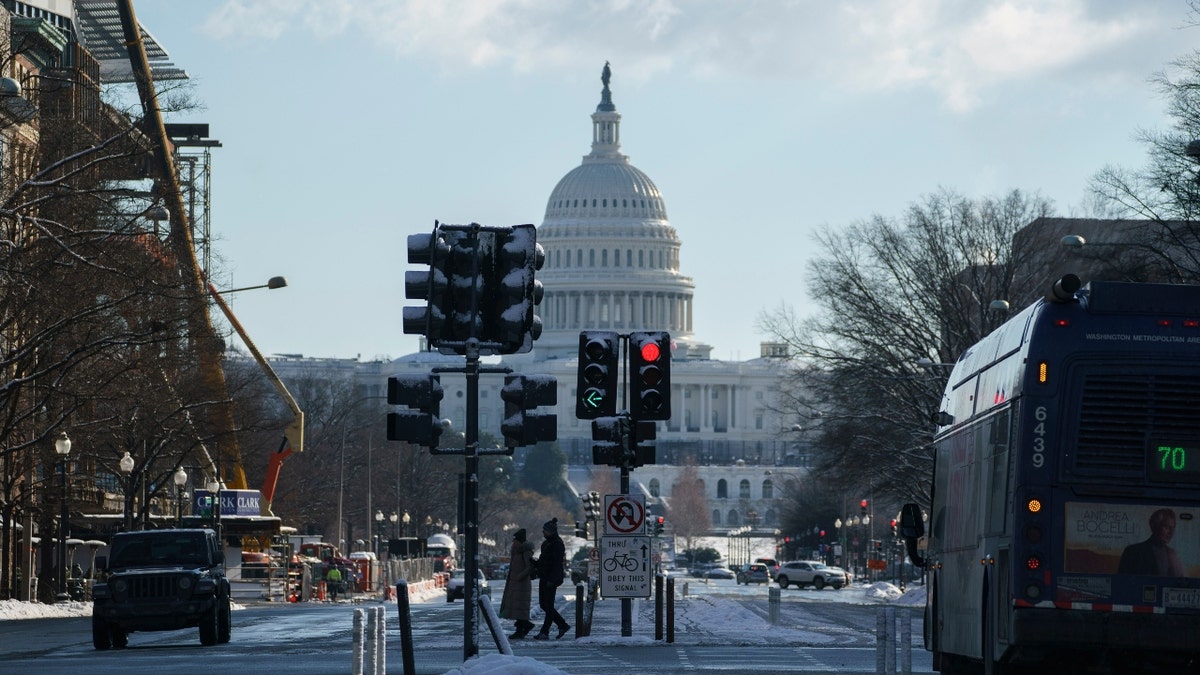 Pedestrians cross Pennsylvania Avenue near the U.S. Capitol in Washington, D.C., U.S., on Friday, Jan. 7, 2022. The House and Senate will both be in session next week for the first time in 2022, and Democratic leaders in both chambers are searching for a path forward on voting rights legislation. Photographer: Ting Shen/Bloomberg