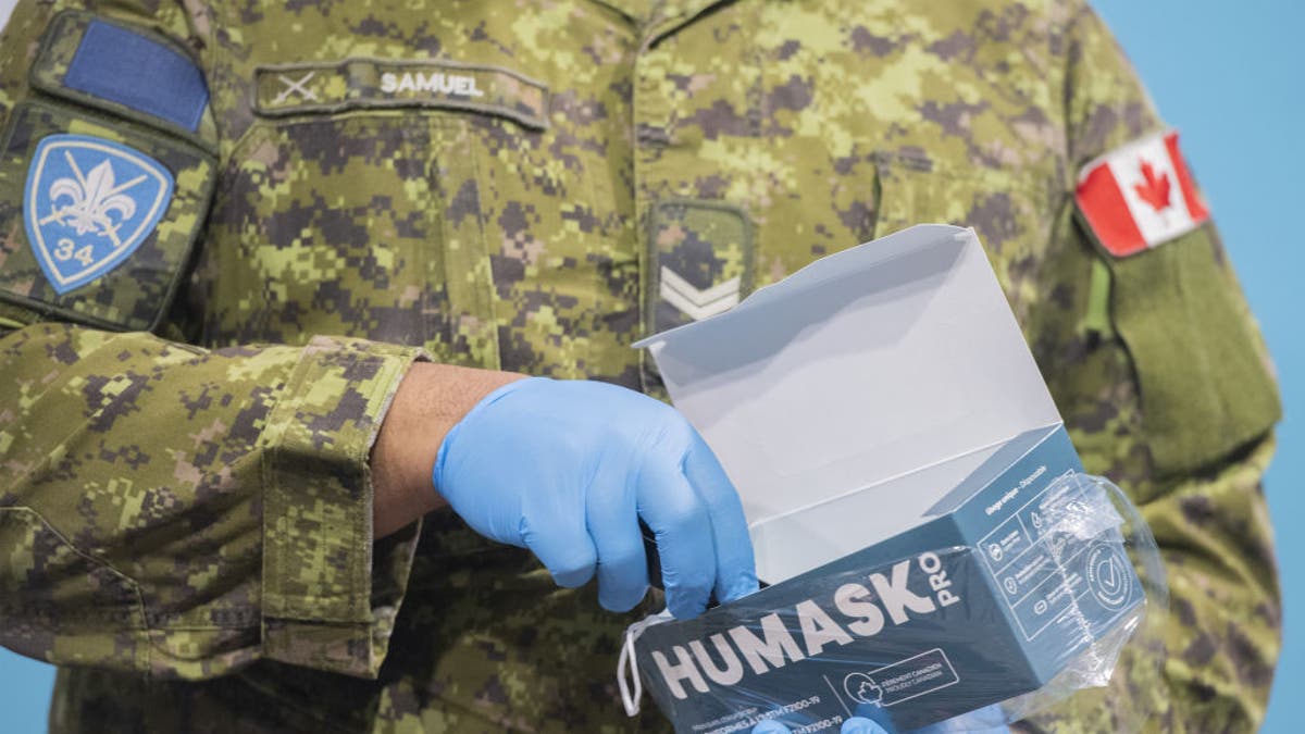 A member of the Canadian Armed Forces holds a box of surgical masks at the Decarie Square Covid-19 vaccination site in Montreal, Quebec, Canada, on Wednesday, Jan. 12, 2022. (Graham Hughes/Bloomberg via Getty Images)