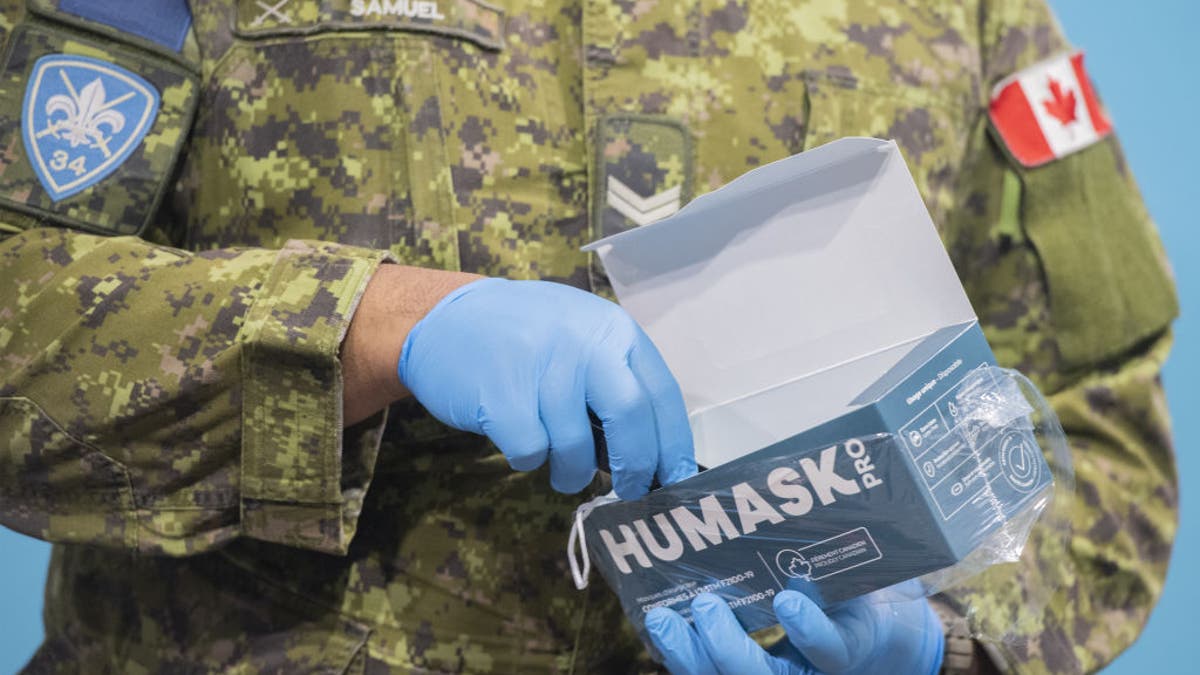 A member of the Canadian Armed Forces holds a box of surgical masks at the Decarie Square Covid-19 vaccination site in Montreal, Quebec, Canada, on Wednesday, Jan. 12, 2022. (Graham Hughes/Bloomberg via Getty Images)