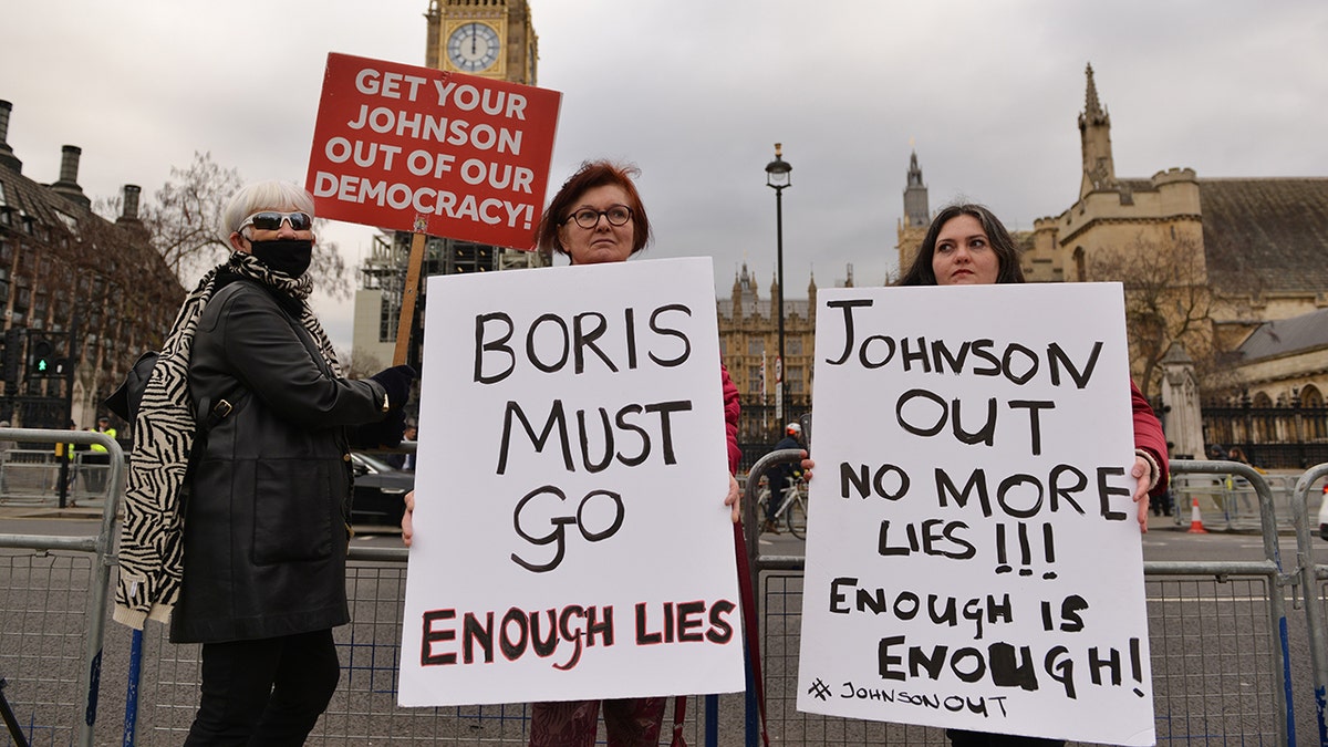 Protesters hold placards expressing their opinion opposite the Houses Of Parliament demanding the prime minister's resignation over Partygate during the demonstration.?