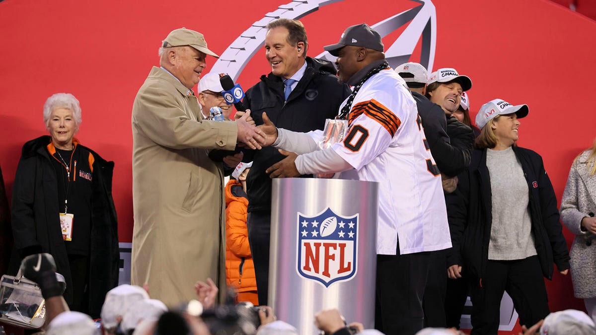 Cincinnati Bengals owner Mike Brown shakes hands with former player Ickey Woods during an interview with CBS announcer Jim Nantz after the Bengals won the game vs. the Kansas City Chiefs at Arrowhead Stadium in Kansas City, Missouri.