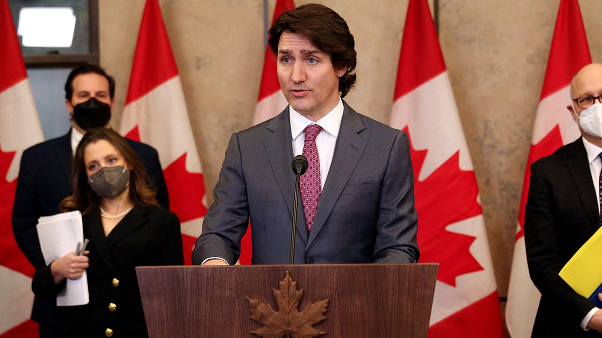 Justin Trudeau at lectern, Canada flags behind him