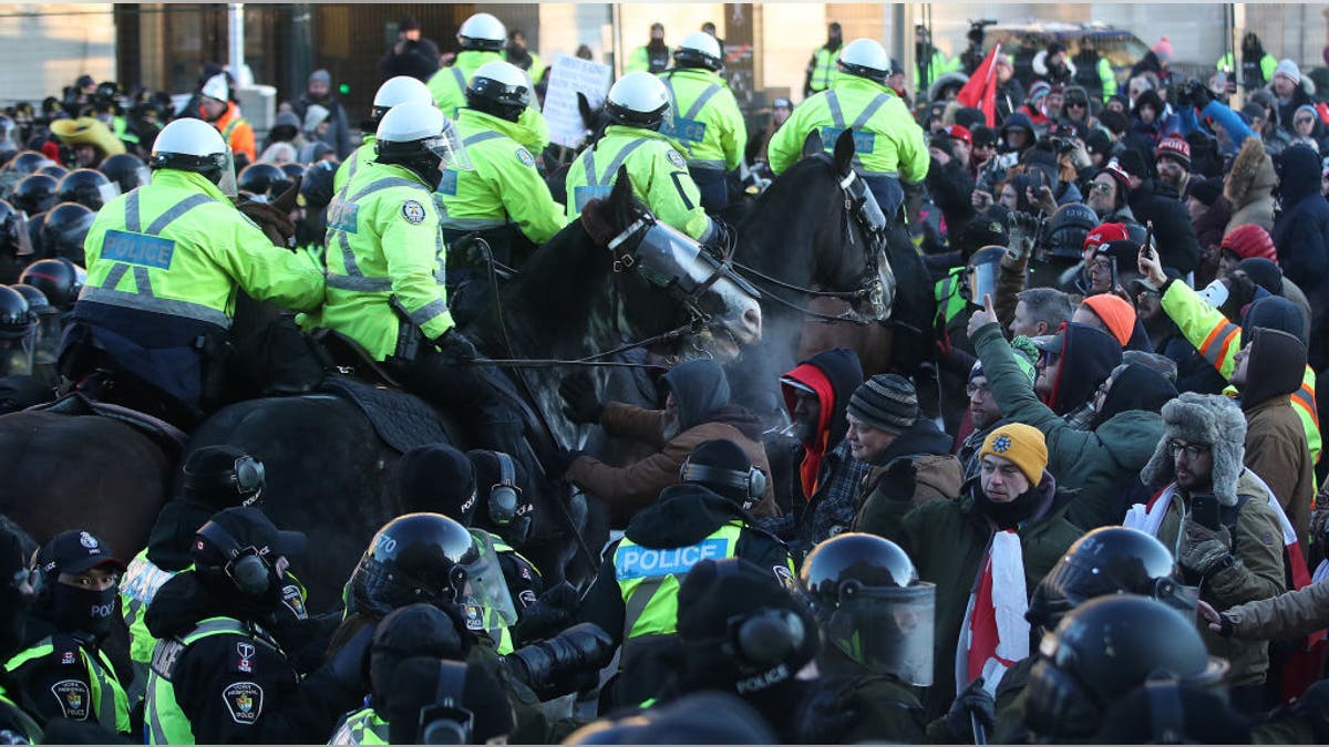 Horses are brought in to disperse the crowd in front of Parliament Hill in Ottawa, on Feb. 18, 2022.