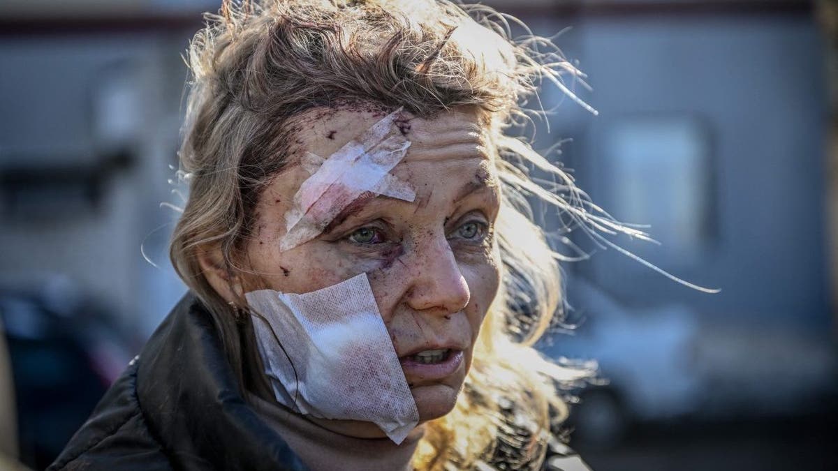 A wounded woman stands outside a hospital after the bombing of the eastern Ukraine town of Chuguiv on February 24, 2022, as Russian armed forces attempt to invade Ukraine from several directions, using rocket systems and helicopters to attack Ukrainian position in the south, the border guard service said. - Russia's ground forces crossed into Ukraine from several directions, Ukraine's border guard service said, hours after President Vladimir Putin announced the launch of a major offensive. Russian tanks and other heavy equipment crossed the frontier in several northern regions, as well as from the Kremlin-annexed peninsula of Crimea in the south, the agency said.