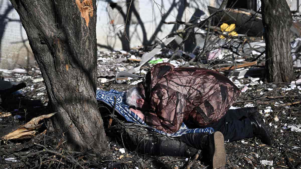 A man reacts at the body of a relative outside a destroyed building after bombings on the eastern Ukraine town of Chuguiv on February 24, 2022