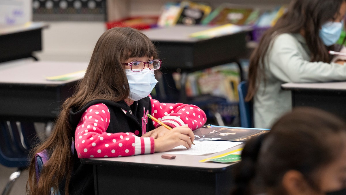 Girl student wearing mask in classroom during COVID pandemic.