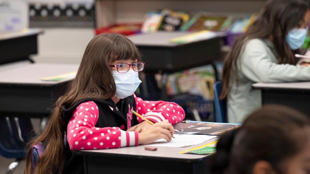 Girl student wearing mask in classroom during COVID pandemic.