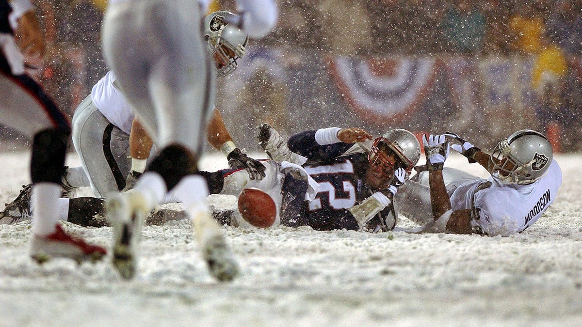 Patriots quarterback Tom Brady loses the ball after being hit by the Oakland Raiders Charles Woodson, right, the fumble was recovered by Greg Biekert, left, but it was ruled an incomplete pass, giving the Patriots another chance.
