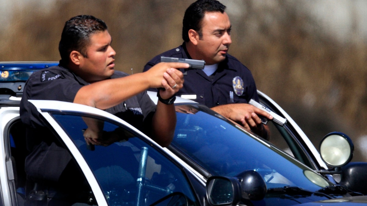 Boster, Mark –– – LOS ANGELES, CA., SEPTEMBER 20, 2010; LAPD officers draw their weapons while they make a felony traffic stop at the corner of Gage and Grand in South Los Angeles after a brown van containing four people suspected of a residential burglary in the Harbor divsion was pulled over September 20, 2010. All four suspects were taken into custody. (Mark Boster/Los Angeles Times)