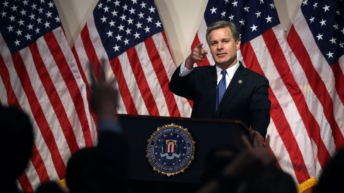 Christopher Wray, FBI director at lectern with US flags