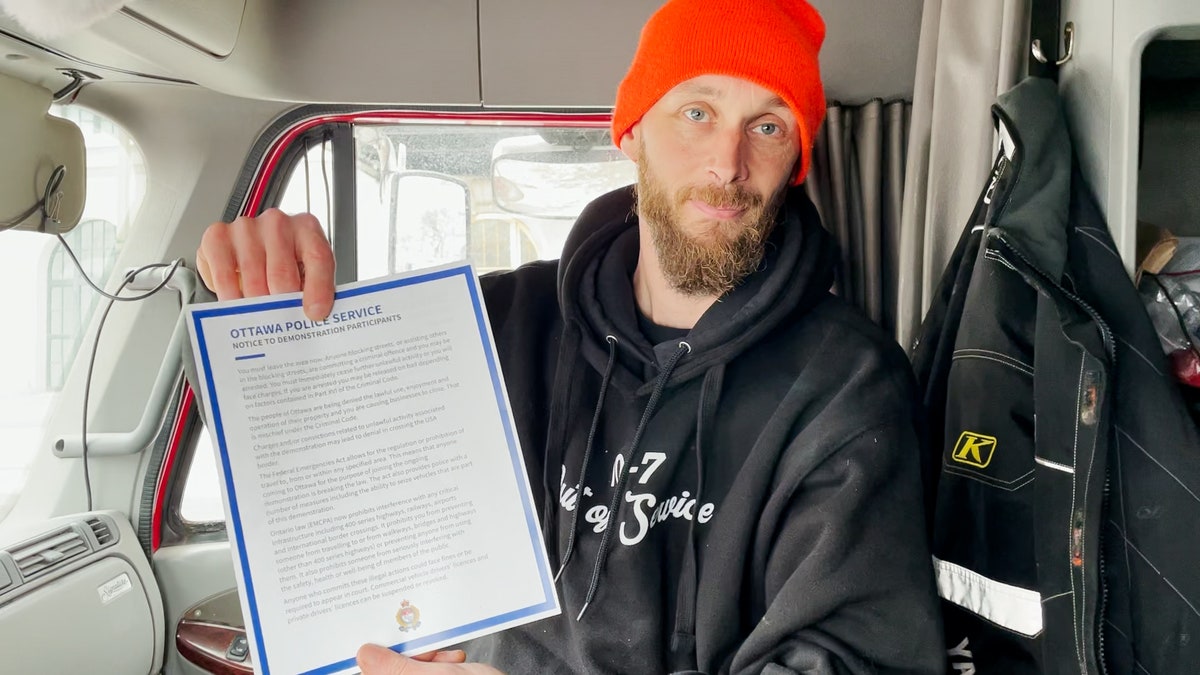 Canadian trucker Mike Anderson holds up the notice warning demonstrators to leave or potentially face arrest.