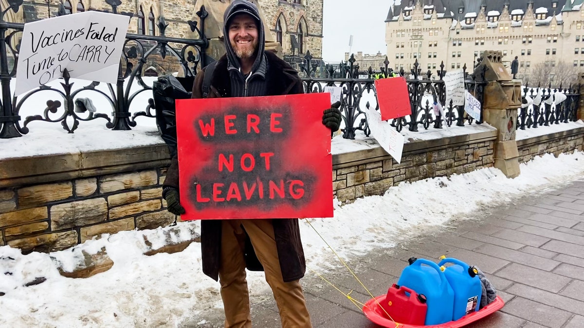 Man holds a sign that says "We're not leaving" in Ottawa at the Freedom Convoy.