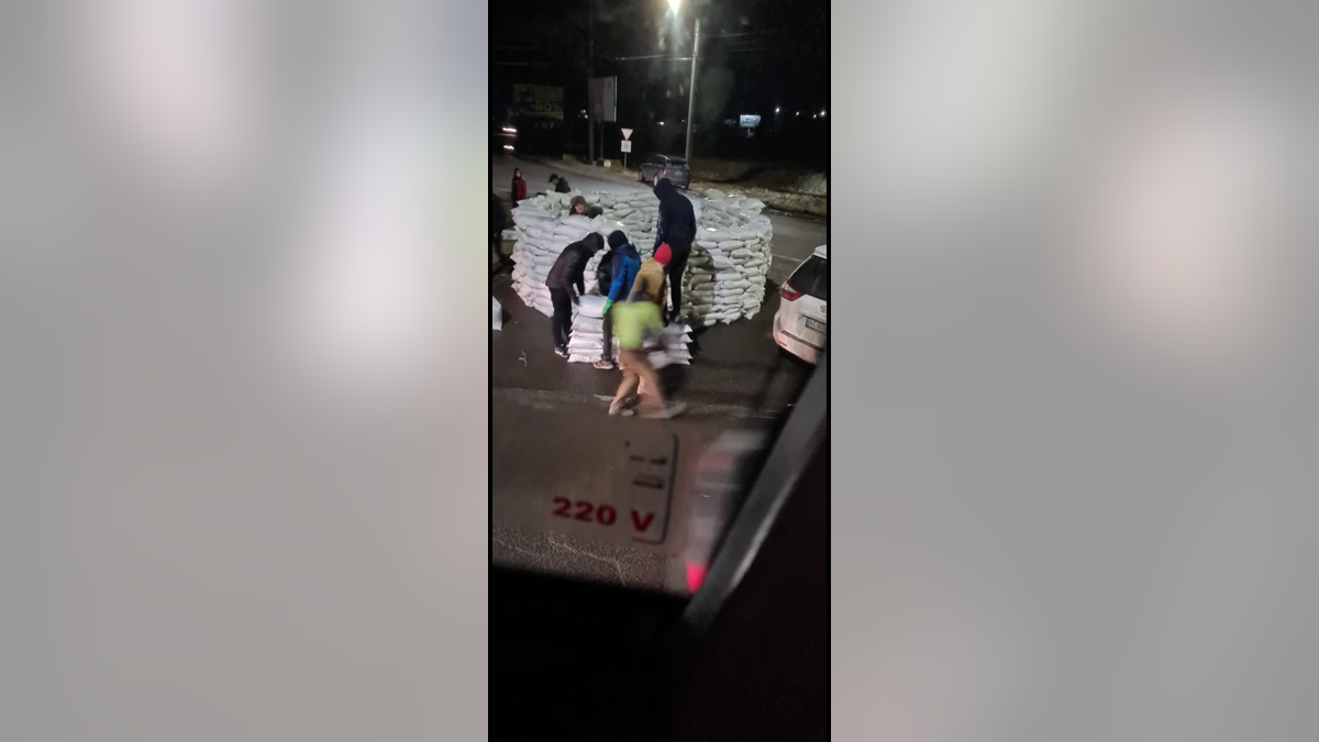 People stacking sandbags on the road between Kyiv and Poland on Friday, Feb. 25, 2022.