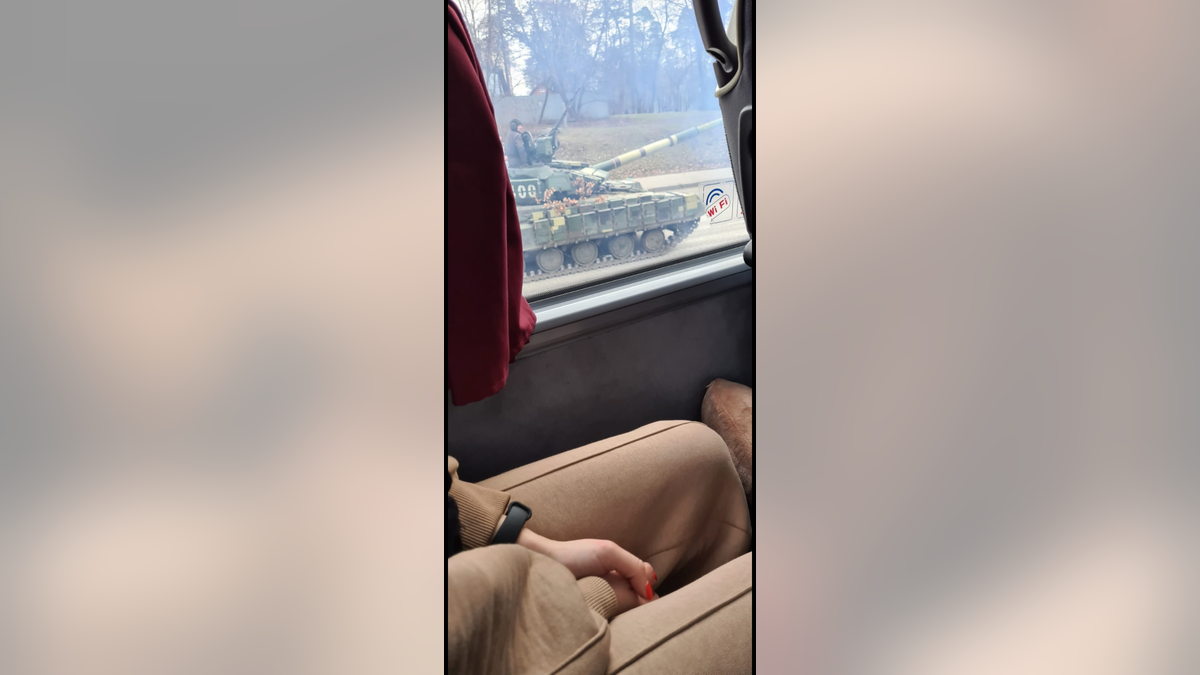 A Ukrainian tank passes a bus carrying travelers from Kyiv toward the border with Poland on Friday, Feb. 25, 2022. Hours later, fighting had reached Ukraine's capital city amid Russia's invasion of the country.