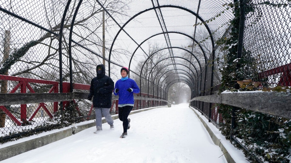 Runners run on a snow covered Monon Trial, Thursday, Feb. 3, 2022, in Indianapolis. A major winter storm with millions of Americans in its path is spreading rain, freezing rain and heavy snow further across the country.